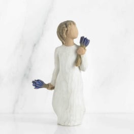 Figurine of a girl in a white dress holding small blue flowers