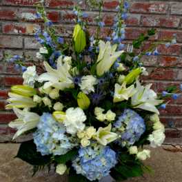 White lilies and blue hydrangeas in a white vase