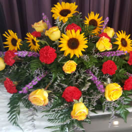 Casket spray with sunflowers, yellow roses, and red carnations