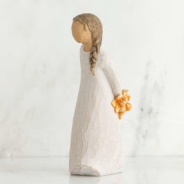 Small figurine of a girl in a white dress holding orange flowers