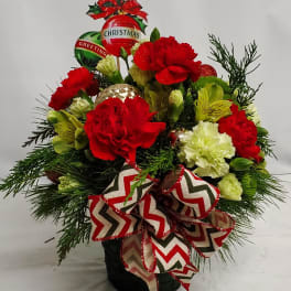 Christmas bouquet with red and white carnations, ornaments, and a chevron ribbon in a black container