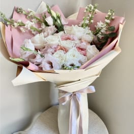 Bouquet of white and blush roses wrapped in pink paper