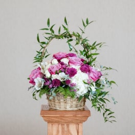 Basket arrangement of pink and white flowers with a leafy arch