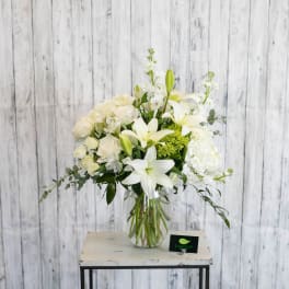 White floral arrangement in a clear glass vase on a small table