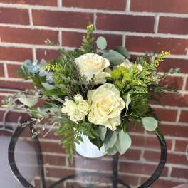 White rose bouquet in a white vase with mixed greenery