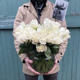 Person holding a vase of white roses