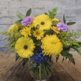 Yellow and purple mixed bouquet in a clear glass vase