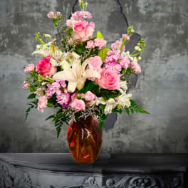Pink and white mixed flower arrangement in an amber glass vase