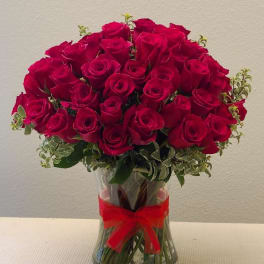 Bouquet of red roses in a clear glass vase with a red ribbon