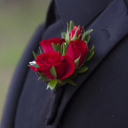 Small red rose boutonniere pinned to a black suit lapel
