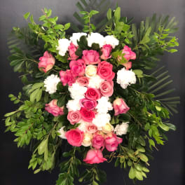 Pink and white rose funeral spray with lush greenery