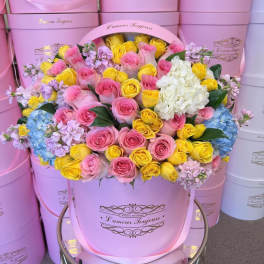Pink hatbox arrangement of roses, hydrangeas, and lilac flowers