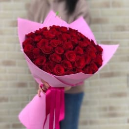 Large bouquet of red roses wrapped in pink paper with long pink ribbons