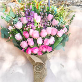 Pink tulips and roses arranged in burlap wrap