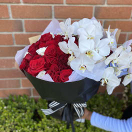 Bouquet of red roses and white orchids wrapped in black paper