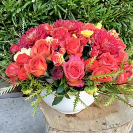 Bouquet of pink and coral roses in a white bowl vase