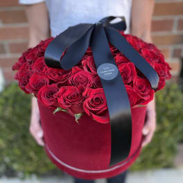 Large red rose bouquet in a round velvet box with a black ribbon