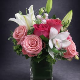Pink roses and white lilies arranged in a clear glass vase