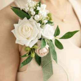 White rose boutonniere with small white blossoms and green leaves