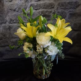 Yellow lilies and white roses arranged in a glass vase