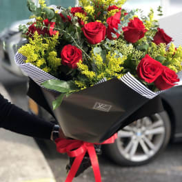 Bouquet of red roses with yellow filler flowers and black wrapping