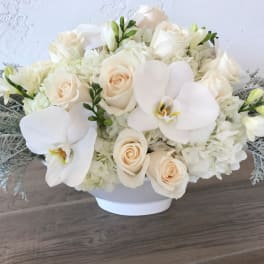 White roses and orchids in a low white bowl