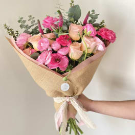 Pink and peach mixed bouquet wrapped in burlap with a ribbon