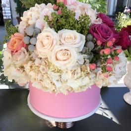Round bouquet of pale roses and hydrangeas in a pink box