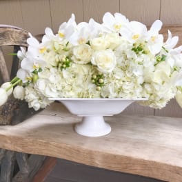 White floral arrangement in a white pedestal bowl