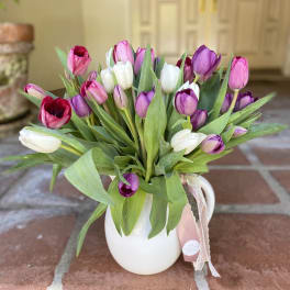 Bouquet of pink, purple, and white tulips in a white pitcher