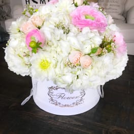 Round bouquet of white and pink flowers in a white hatbox