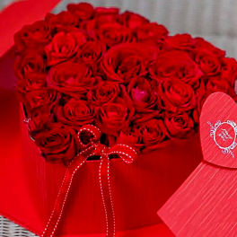 Heart-shaped box filled with red roses and tied with a red ribbon