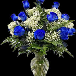 Blue roses and white filler flowers in a clear glass vase