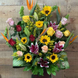 Tall mixed bouquet with sunflowers, roses, lilies, and bird of paradise in a vase