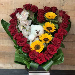 Heart-shaped bouquet of red roses, sunflowers, orchids, and a teddy bear