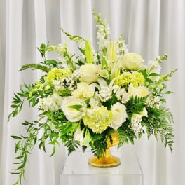 White and pale yellow floral arrangement in a gold vase