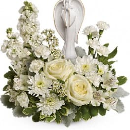 White floral arrangement with roses and daisies around an angel figurine