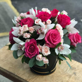 Bouquet of hot pink and pale pink roses with white orchids in a black box