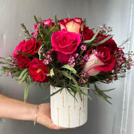 Pink and red roses arranged in a white vase