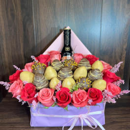 Box arrangement of red and pink roses with chocolates and a Baileys bottle