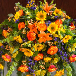 Large mixed floral spray with orange roses, lilies, and yellow sunflowers