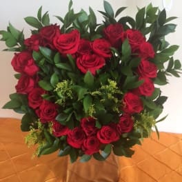 Heart-shaped bouquet of red roses with greenery in a box