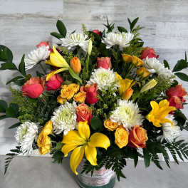 Mixed bouquet of yellow lilies, roses, and white chrysanthemums in a vase