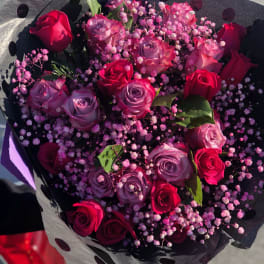 Bouquet of red and lavender roses with pink baby's breath in black polka-dot wrap