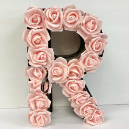 Pink rose-covered letter R decoration on a black base