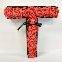 T-shaped box arrangement of coral roses with a black ribbon bow