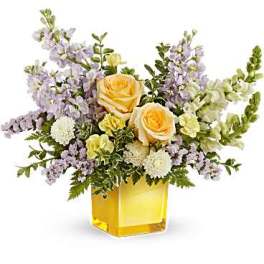 Yellow roses and lavender flowers in a square glass vase