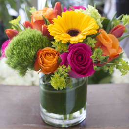 Colorful bouquet of roses and a yellow gerbera daisy in a glass vase