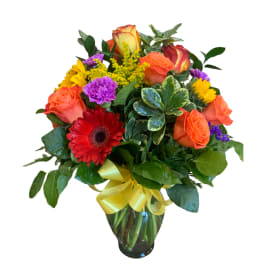 Mixed bouquet of roses, gerbera daisies, and carnations in a glass vase