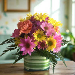 Colorful bouquet of daisies and carnations in a striped ceramic vase
